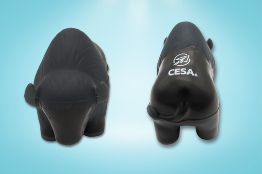 Image of a buffalo-shaped stress reliever toy shown from two angles on a light blue background. The left side displays a front view of the buffalo, with small ears and simple facial features. The right side shows a back view with the white CESA 6 logo printed on its back. The toy has a smooth, matte surface with subtle molded texture to represent fur.
