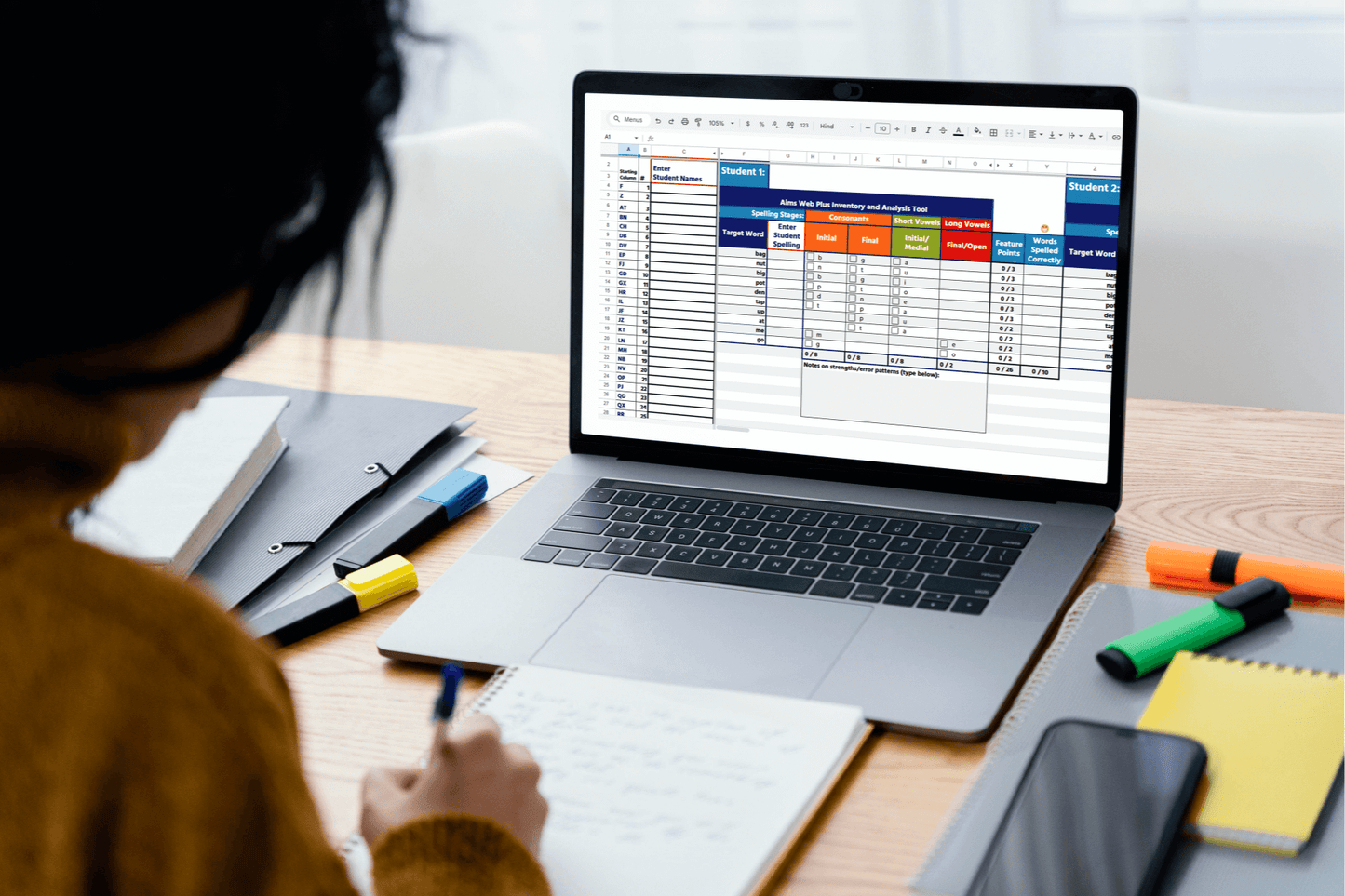 Educator analyzing student data on a laptop, using a structured spreadsheet for assessment. The workspace includes organized materials, high-contrast digital content, and a well-lit environment to support accessibility and efficient data-driven instruction.