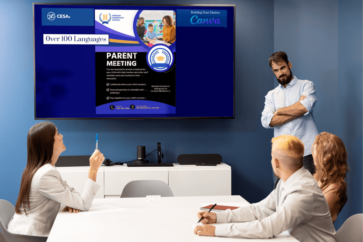 A business meeting with four people watching a presentation on a screen. The slide announces a "Parent Meeting" in over 100 languages.