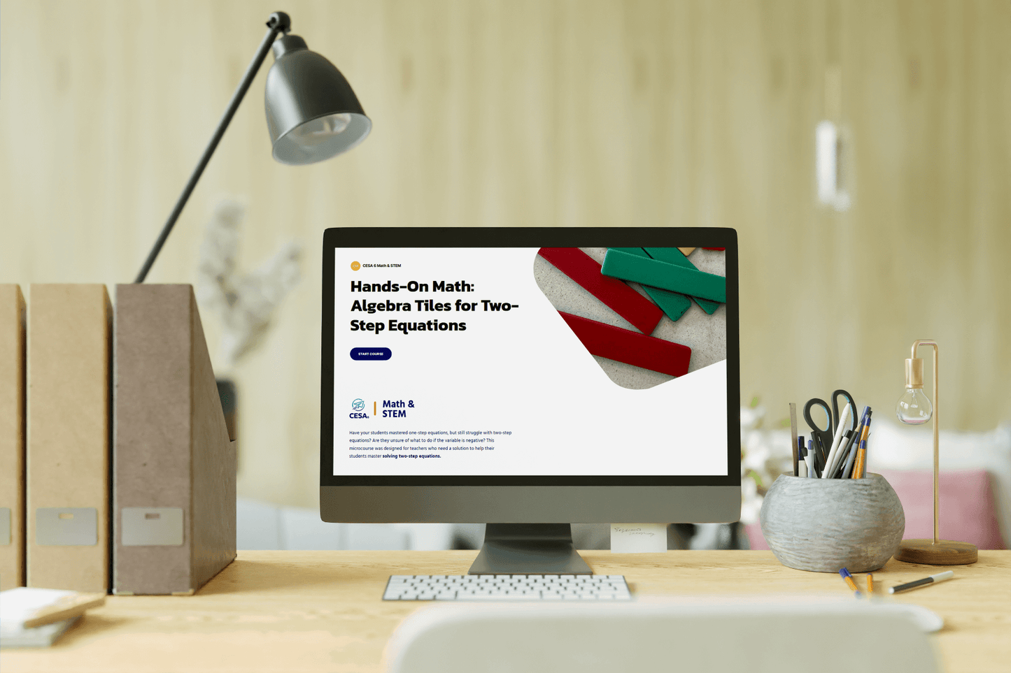 A modern desk setup with a computer screen displaying a math course titled "Hands-On Math: Algebra Tiles for Two-Step Equations." The scene feels educational and organized.