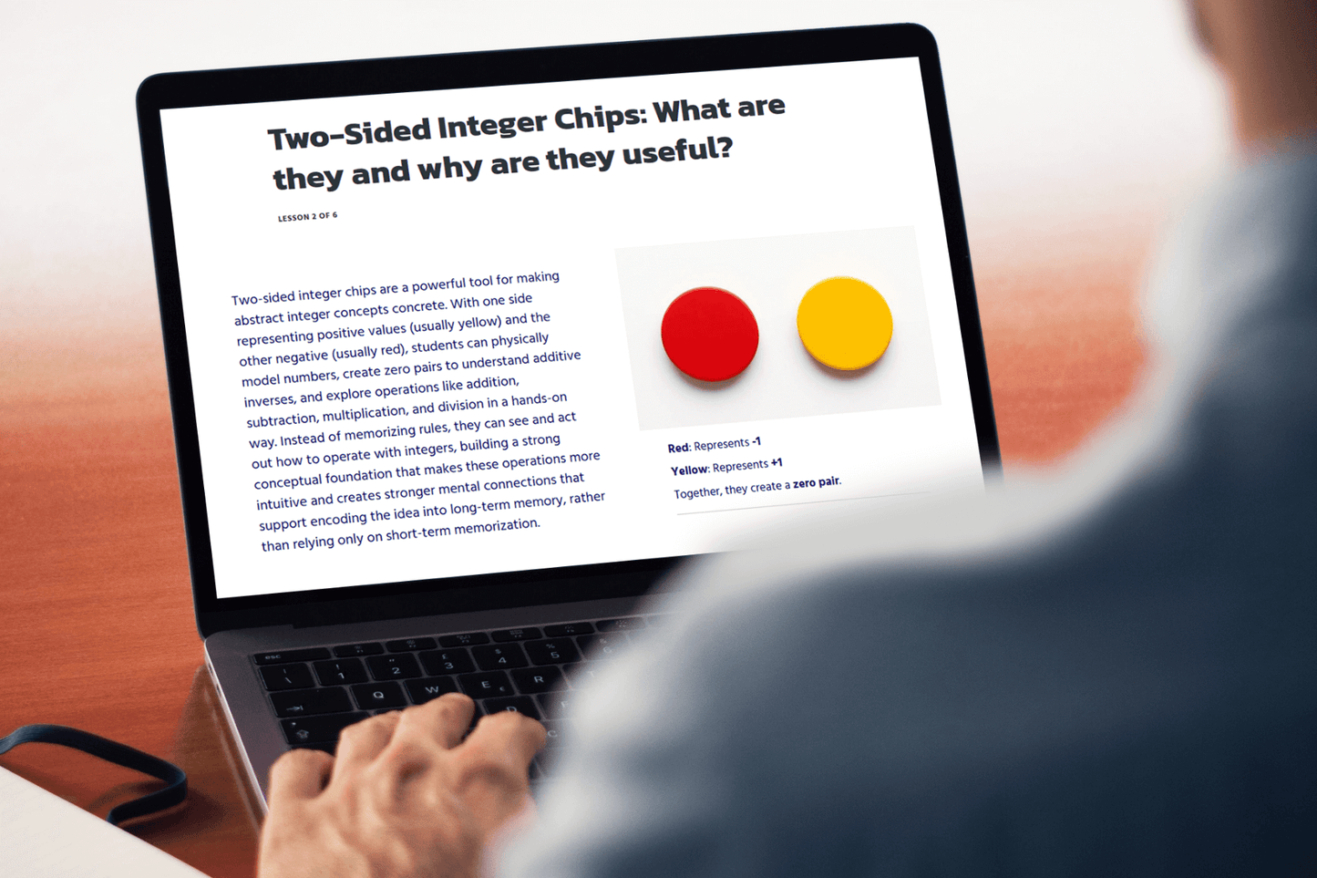 A person reads an article on a laptop titled "Two-Sided Integer Chips: What are they and why are they useful?" It features red and yellow chips.