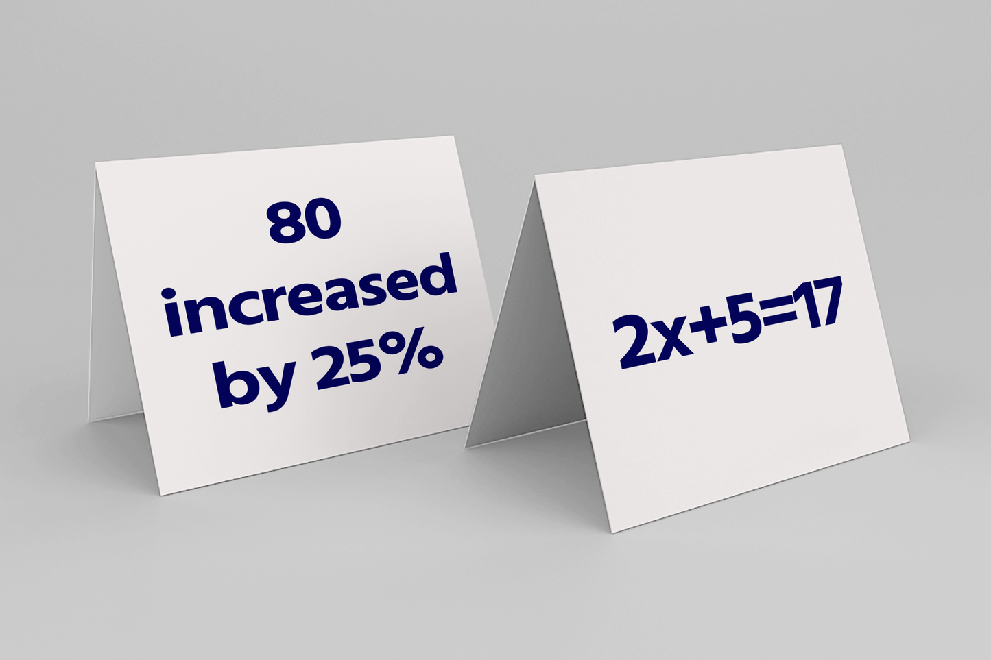 Two folded cards on a gray surface; the left card reads "80 increased by 25%," and the right card shows "2x+5=17," both in bold navy blue font.