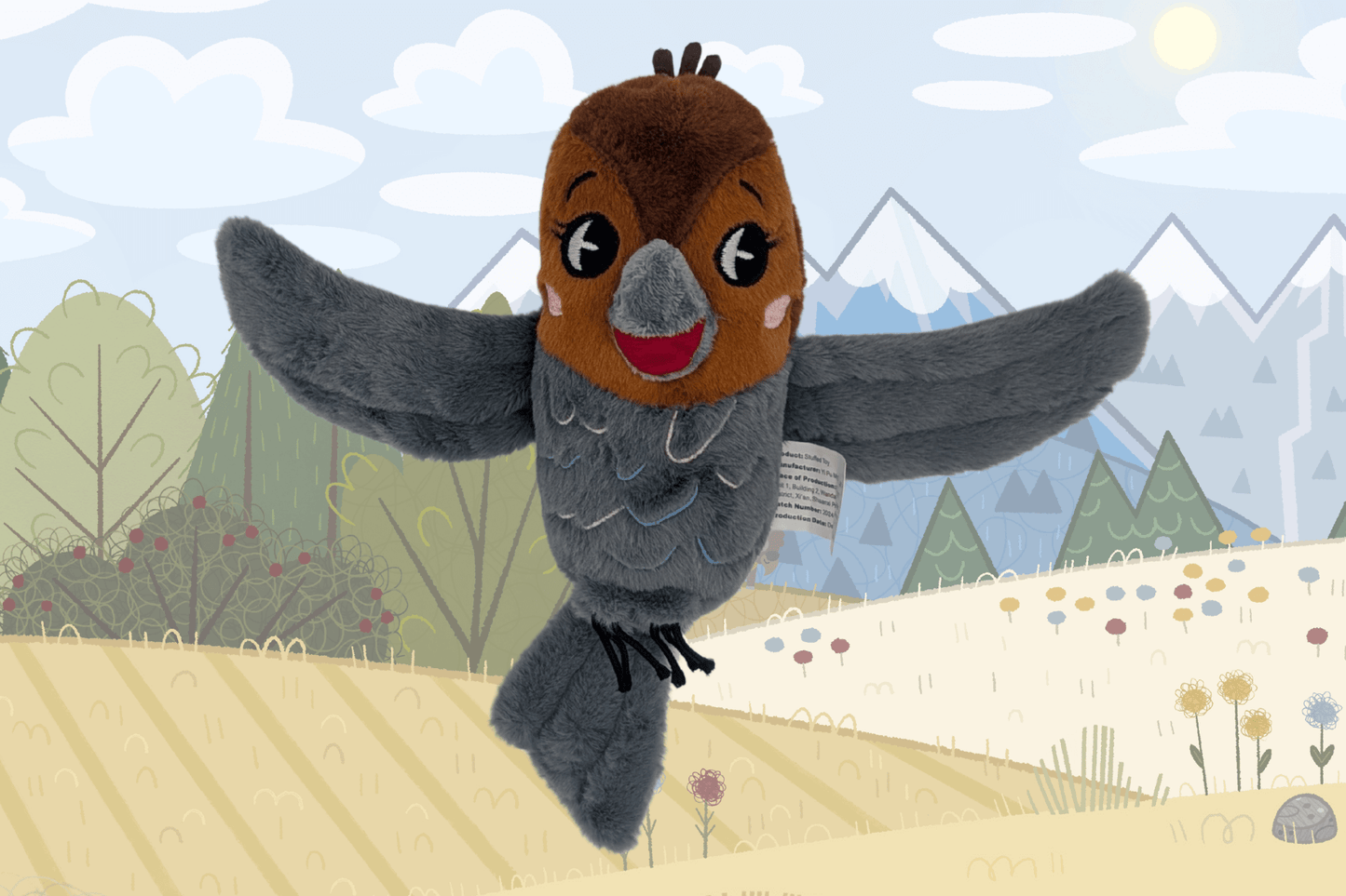 This image features the front view of a plush bird named Tootsie, positioned in front of a softly illustrated outdoor landscape with trees, flowers, and snow-capped mountains. Tootsie has soft, textured wings spread wide, a dark gray body with stitched feather detailing, and a cheerful expression. The bird’s face is rust-colored with embroidered eyes, a smiling red mouth, and pink blush marks on the cheeks. A white manufacturer’s tag is visible on the side of the plush.