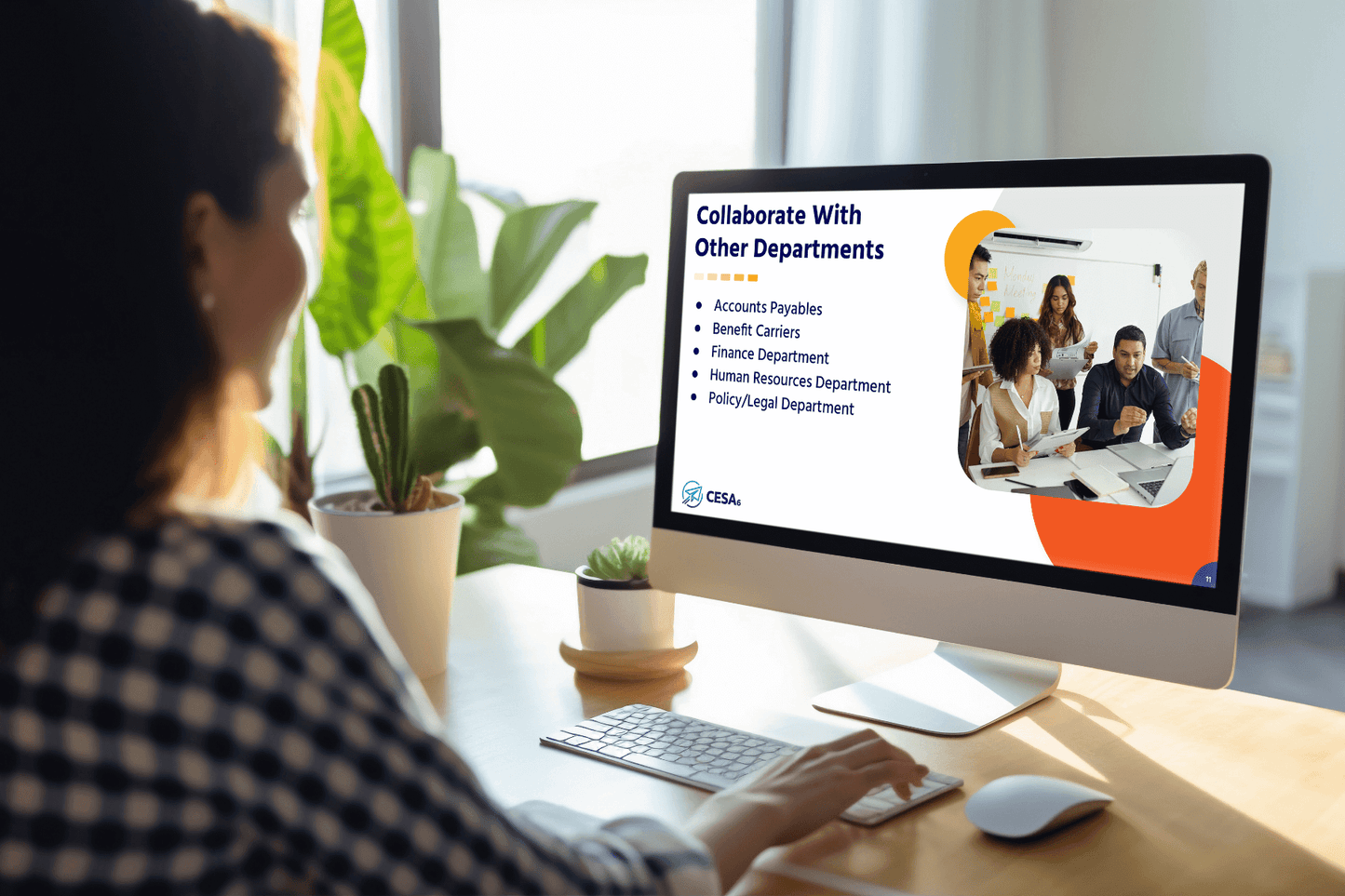 A woman in a checkered shirt is at a desk, looking at a computer displaying a presentation slide titled "Collaborate With Other Departments." The slide lists departments such as Accounts Payables and Human Resources. A group of colleagues appears in a photo on the slide. Bright and professional setting.
