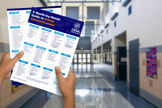 Hands holding a "Month-by-Month Guide to School Communications" pamphlet, featuring monthly sections. Background shows a bright, modern school hallway.