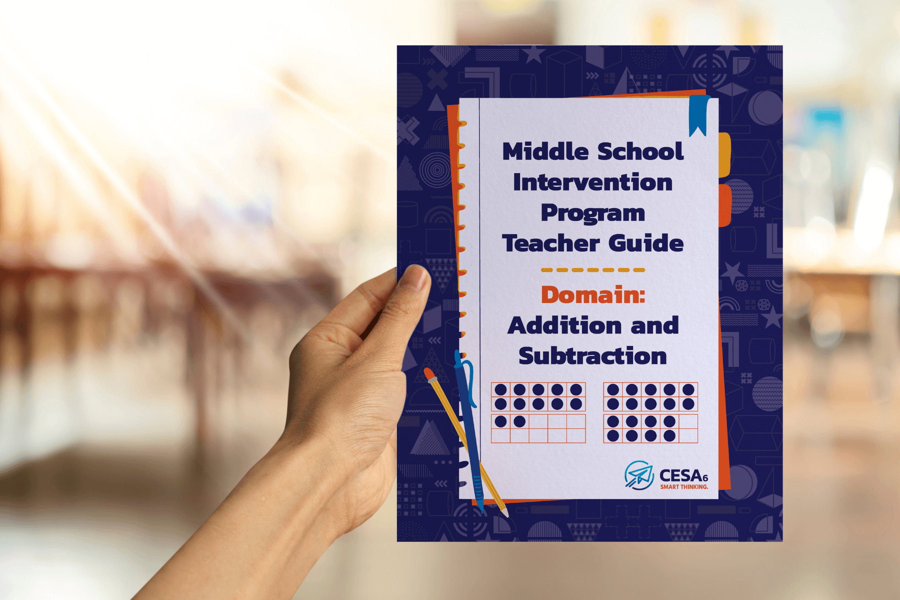 A hand holds a "Middle School Intervention Program Teacher Guide" for addition and subtraction. The background is a blurred classroom.