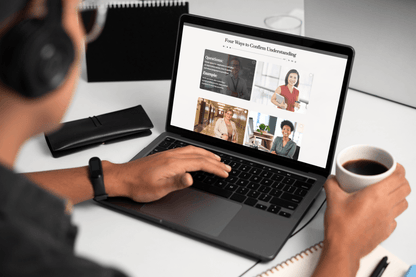 A person wearing headphones reads an online wellness article on a laptop while holding coffee, creating a quiet, focused home-office scene.