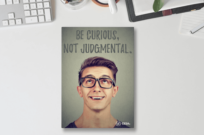 A motivational poster with the phrase “Be Curious, Not Judgmental” in bold text. The design shows a smiling person looking upward with the CESA 6 logo at the bottom.