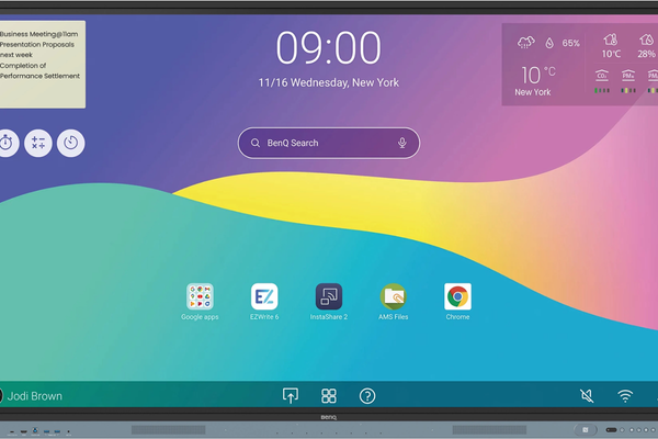 A BenQ interactive display showing the home screen with the current time, weather, and various app icons, including Google apps, EZWrite, InstaShare 2, AMS Files, and Chrome.
