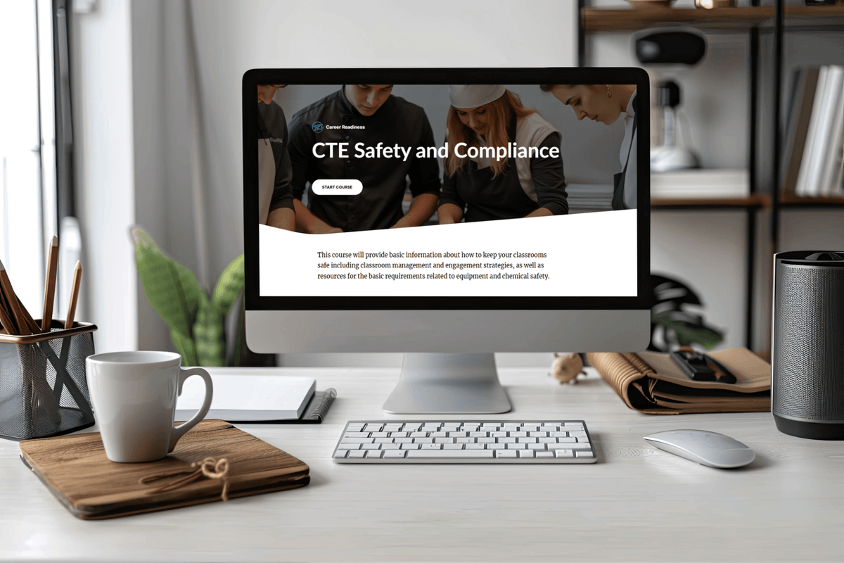 Desktop computer displays a “CTE Safety and Compliance” course page in a bright office, with keyboard, coffee mug, books, and plants.