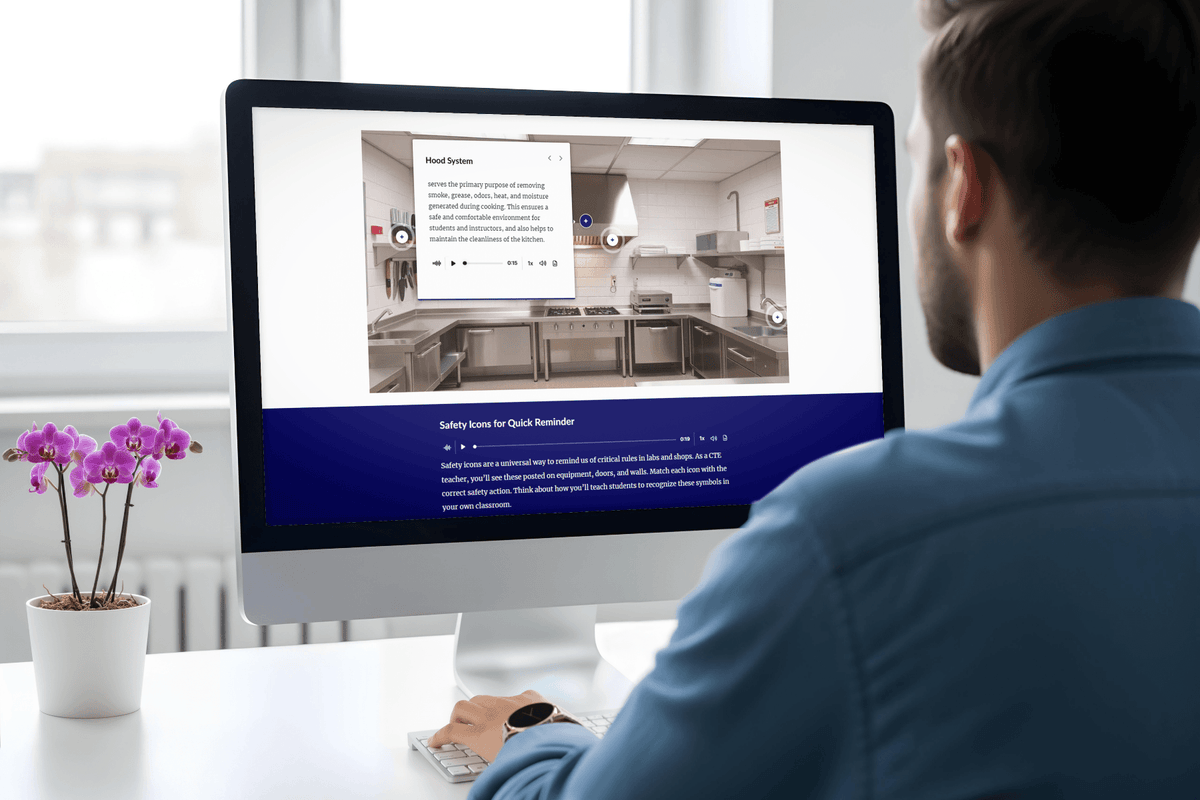 Man in a blue shirt views an interactive kitchen training page on a desktop computer, featuring a kitchen photo, text, and a purple orchid nearby.