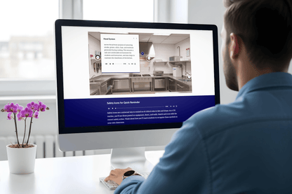 Man in a blue shirt views an interactive kitchen training page on a desktop computer, featuring a kitchen photo, text, and a purple orchid nearby.