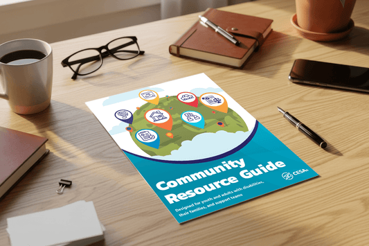 A community resource guide on a wooden table surrounded by a coffee cup, glasses, a notebook, and pens, conveys an organized and professional tone.