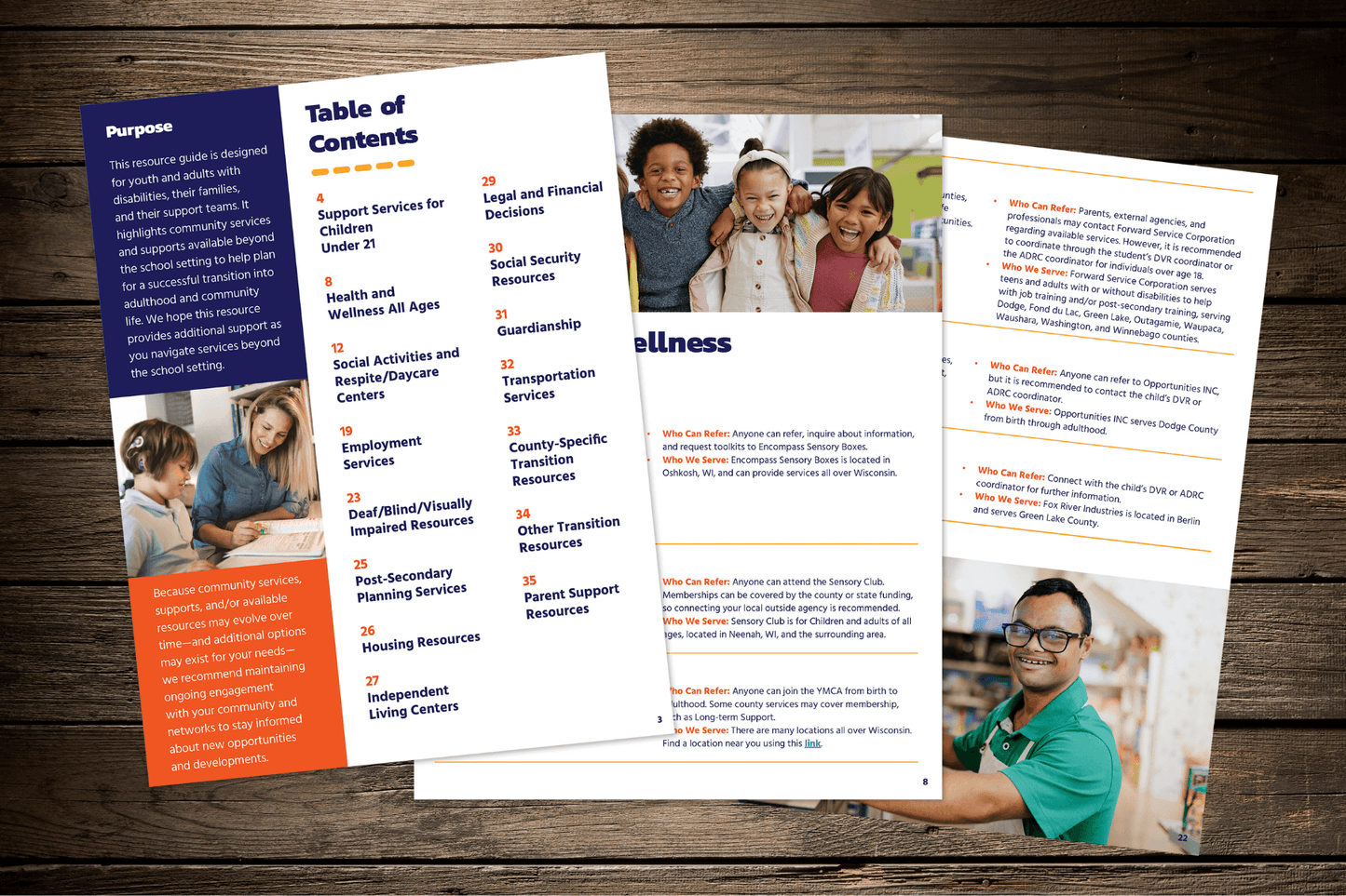 Pamphlets on a wooden table feature a table of contents listing support services, images of smiling children and a man. Tone is supportive and informative.