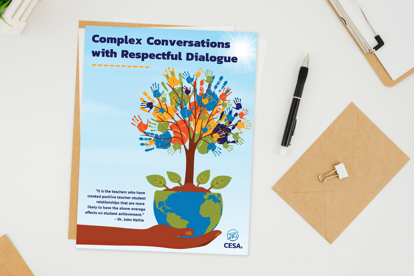 Document titled "Complex Conversations with Respectful Dialogue" on a desk. Features a hand holding a tree with colorful handprints as leaves. Positive and collaborative tone.