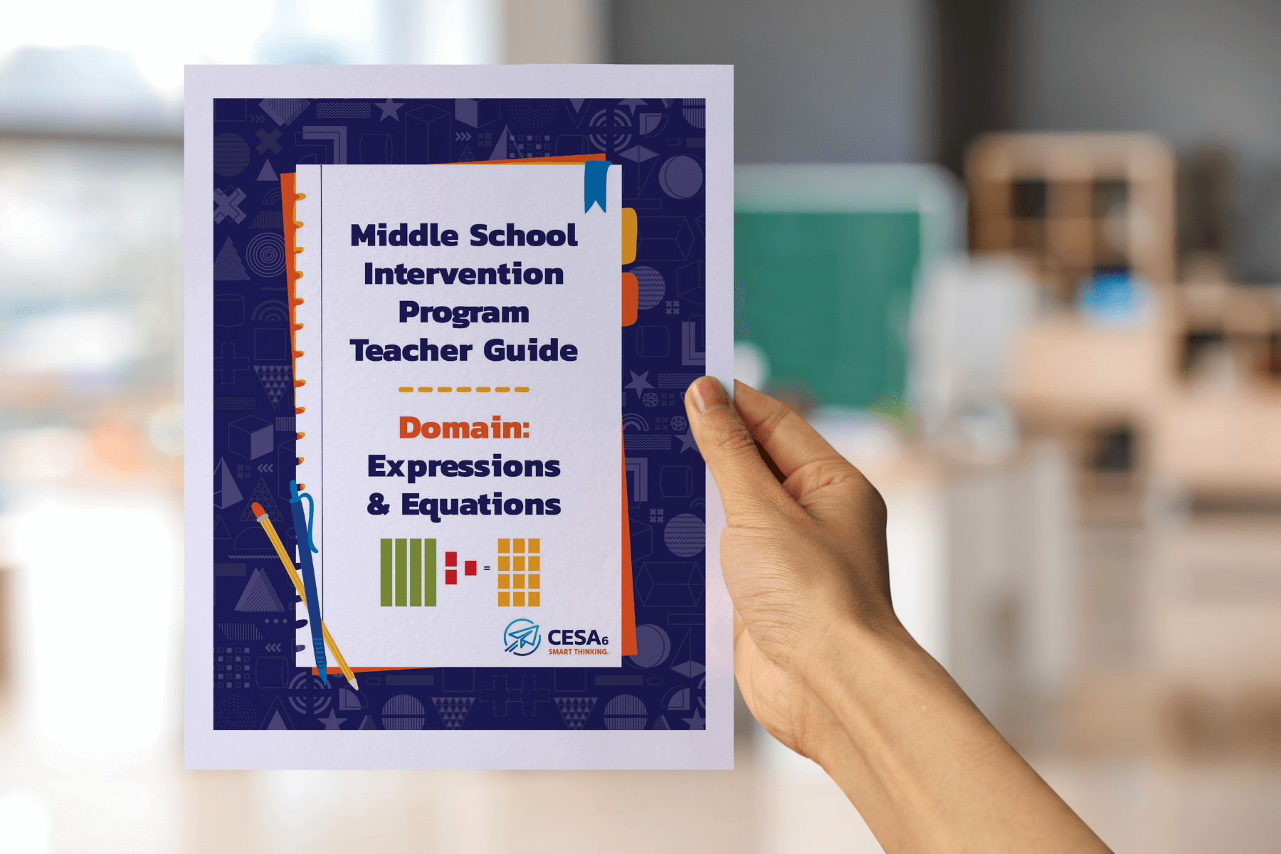 A hand is holding a booklet titled Middle School Intervention Program Teacher Guide: Domain: Expressions & Equations. The cover is decorated with math-themed icons along the border and shows visuals of algebra tiles representing expressions. The CESA 6 logo appears at the bottom. In the background, a blurred classroom with desks and shelves is visible.