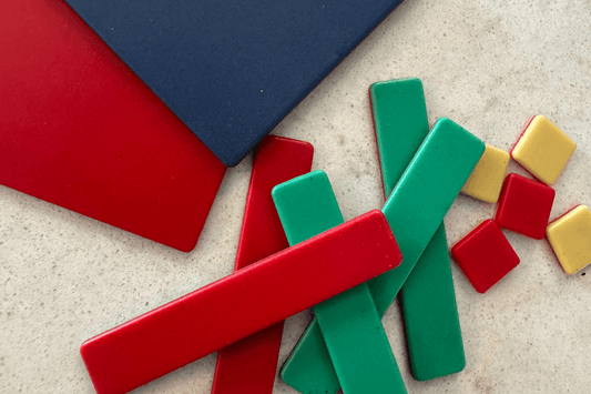 Colorful rectangular and square tiles are scattered on a speckled surface. Tiles include red, green, blue, and yellow, evoking a playful tone.