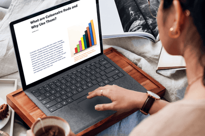 A person reads an article on a laptop titled "What are Cuisenaire Rods and Why Use Them?" The screen shows colorful Cuisenaire Rods.