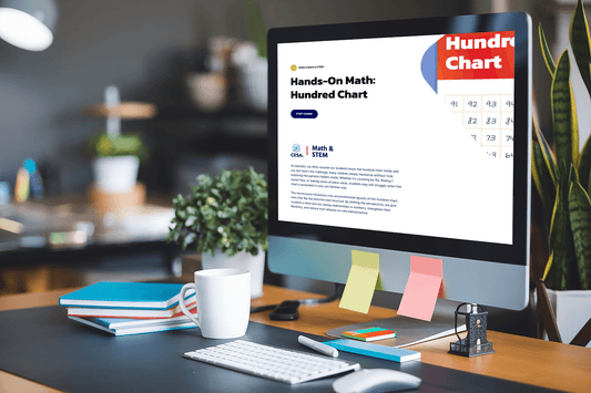 A desk with a computer displaying a webpage titled "Hands-On Math: Hundred Chart." Desk items include a plant, books, a mug, and colorful sticky notes.