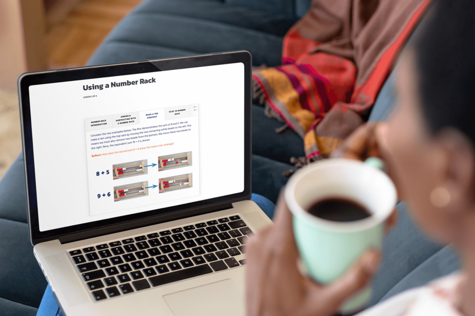 Person holding a mug while viewing a math lesson on a laptop, focused on using a number rack. Cozy, engaged learning atmosphere.
