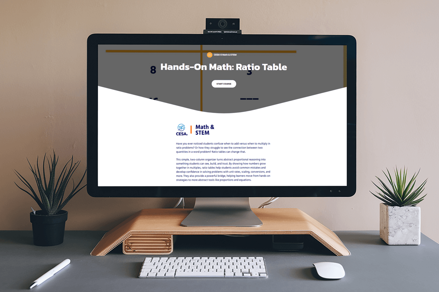 A computer screen displays a "Hands-On Math: Ratio Table" course webpage. The desk features minimalistic decor with two small potted plants, creating a modern, organized workspace.