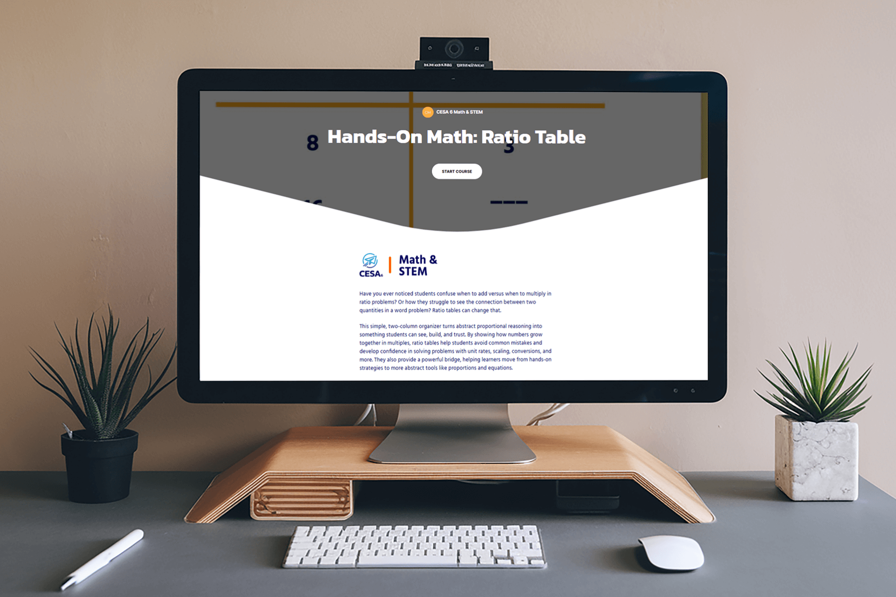 A computer screen displays a "Hands-On Math: Ratio Table" course webpage. The desk features minimalistic decor with two small potted plants, creating a modern, organized workspace.