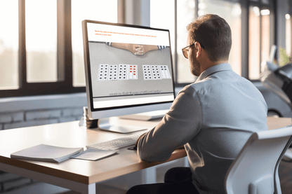 A man sits at a desk in a modern office, focused on a computer screen displaying a video how use Ten-Frames. The sunlight filters through large windows.