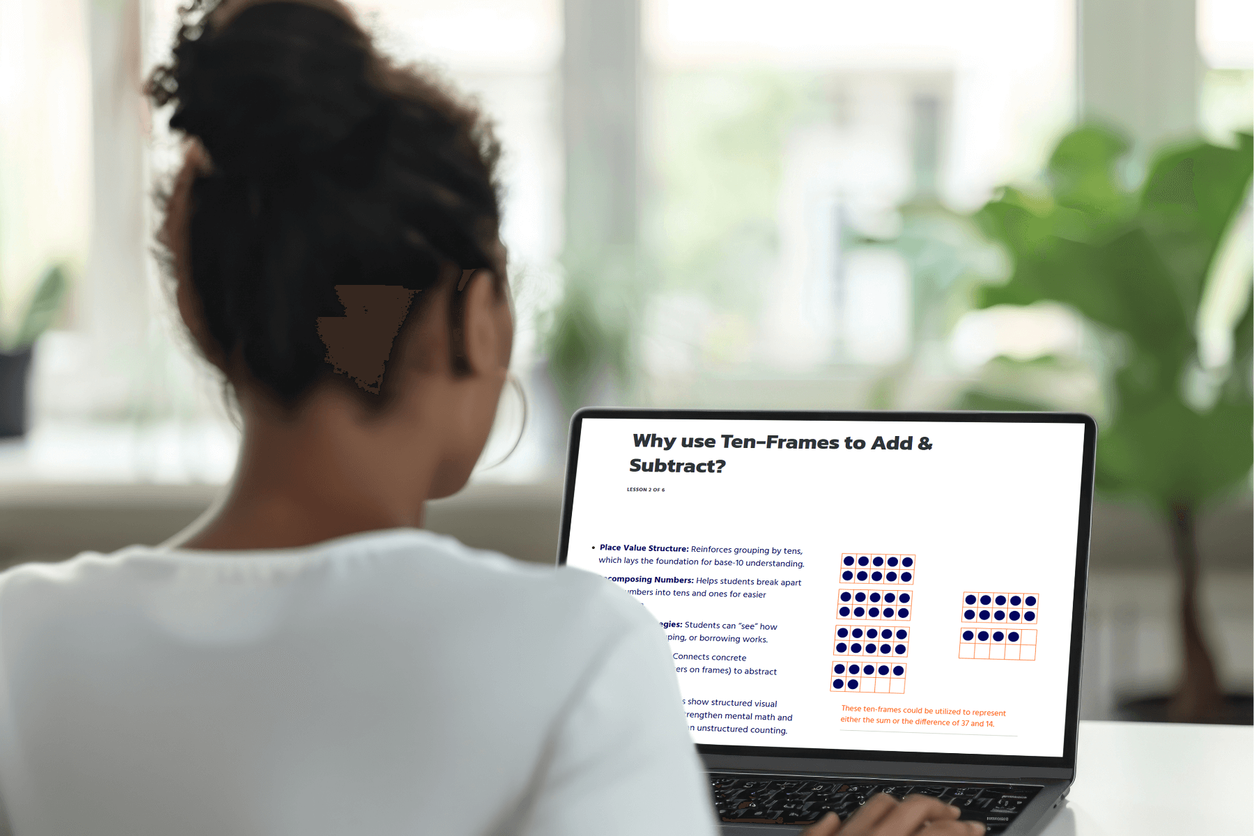A woman in a white shirt works on a laptop showing an article titled "Why use Ten-Frames to Add & Subtract?" The screen displays text and colorful diagrams. Bright, airy background.
