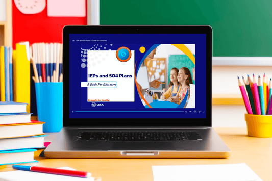 A laptop sits on a classroom desk with the screen displaying an educational slide titled “IEPs and 504 Plans: A Guide for Educators.” The slide features a modern design with blue, orange, and white accents. On the right side of the slide is a circular image of a teacher smiling at two young students in a classroom. The content is labeled "Brought to You By: CESA 6." Around the laptop are colorful school supplies.