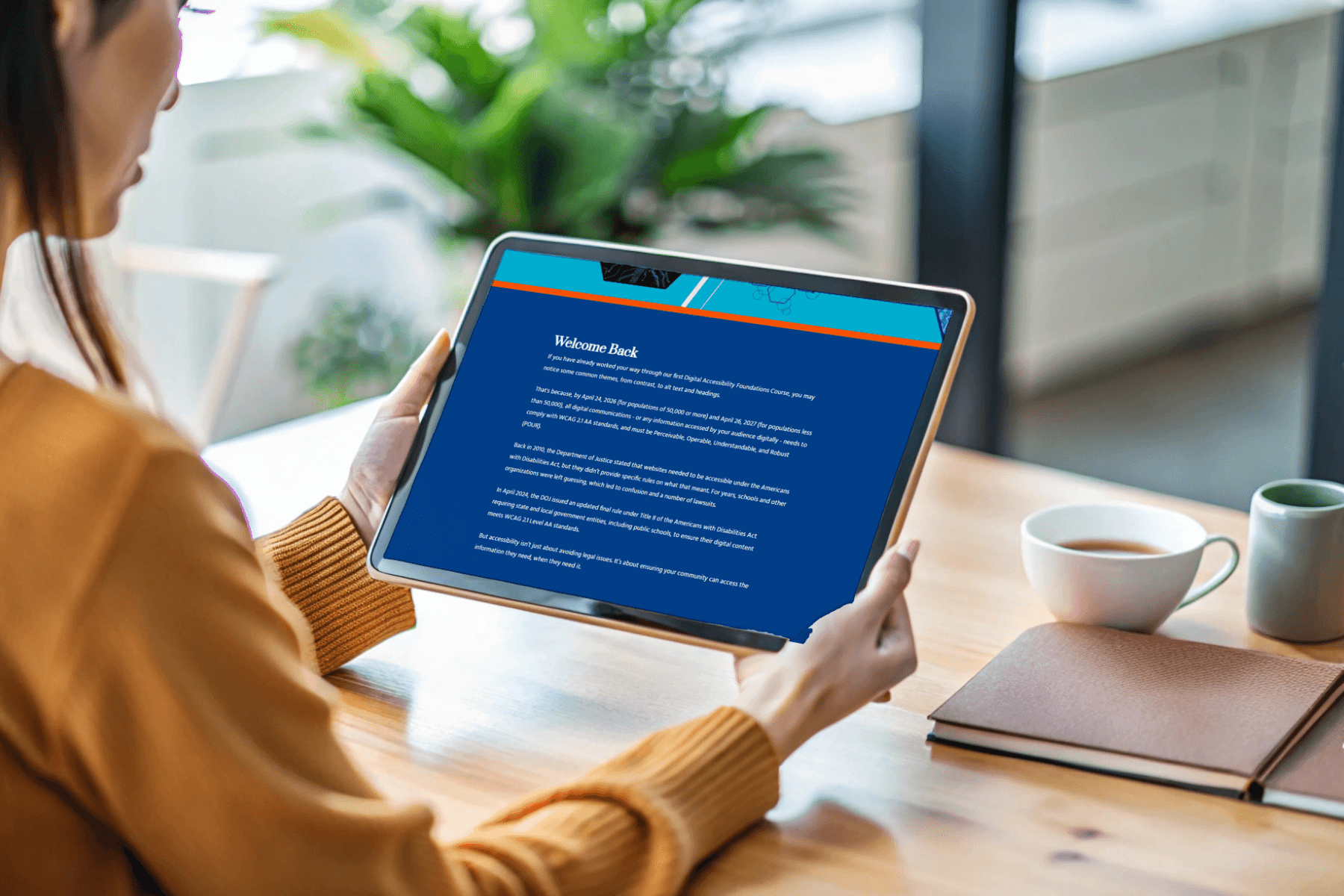 A woman in a cozy sweater holds a tablet displaying a "Welcome Back" message on a blue screen. A notebook and coffee mugs sit on the table, creating a warm atmosphere.