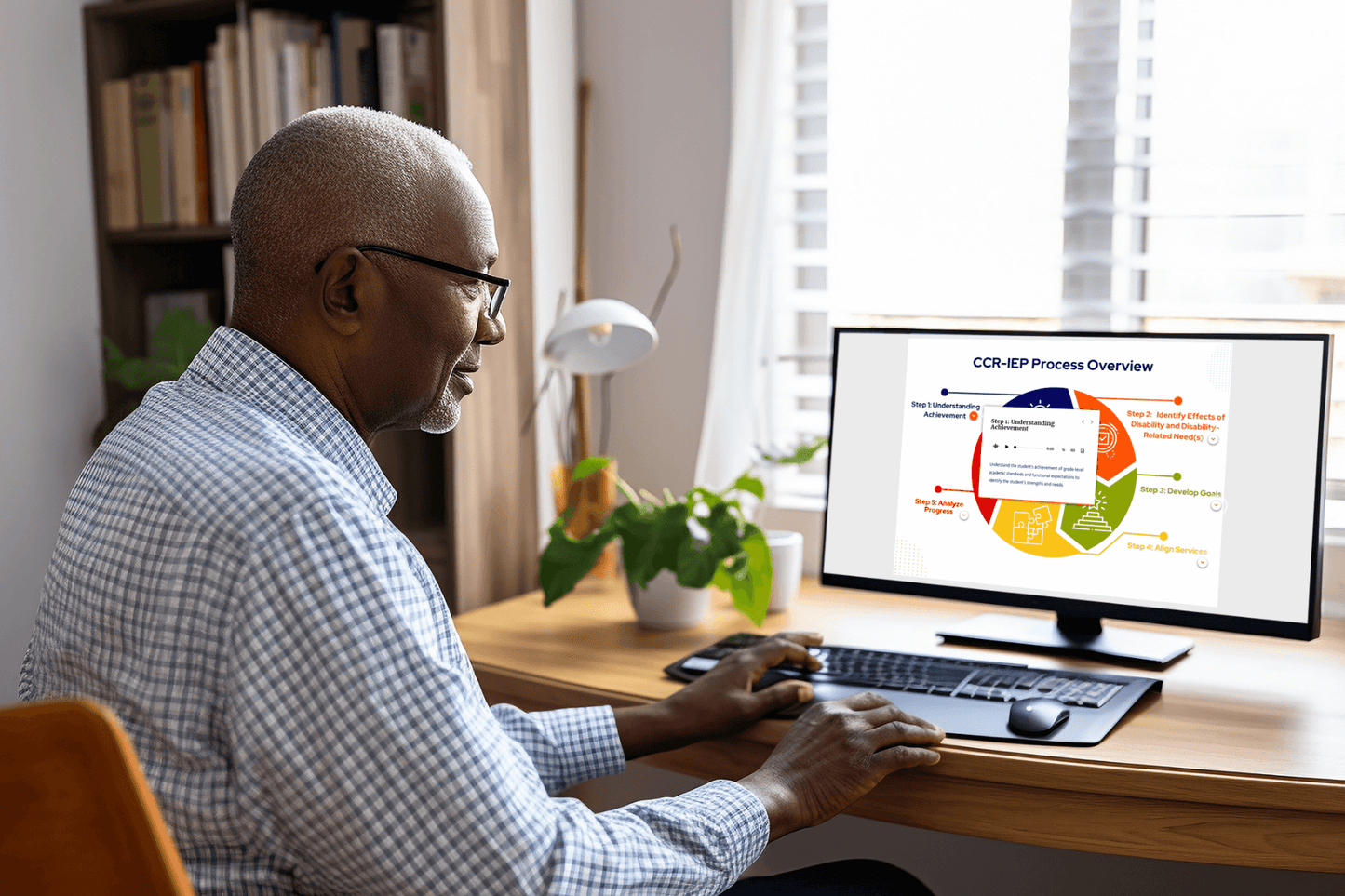 A person in glasses sits at a desk, focused on a computer with a colorful CCR-IEP Process Overview chart. Sunlight filters through nearby windows.