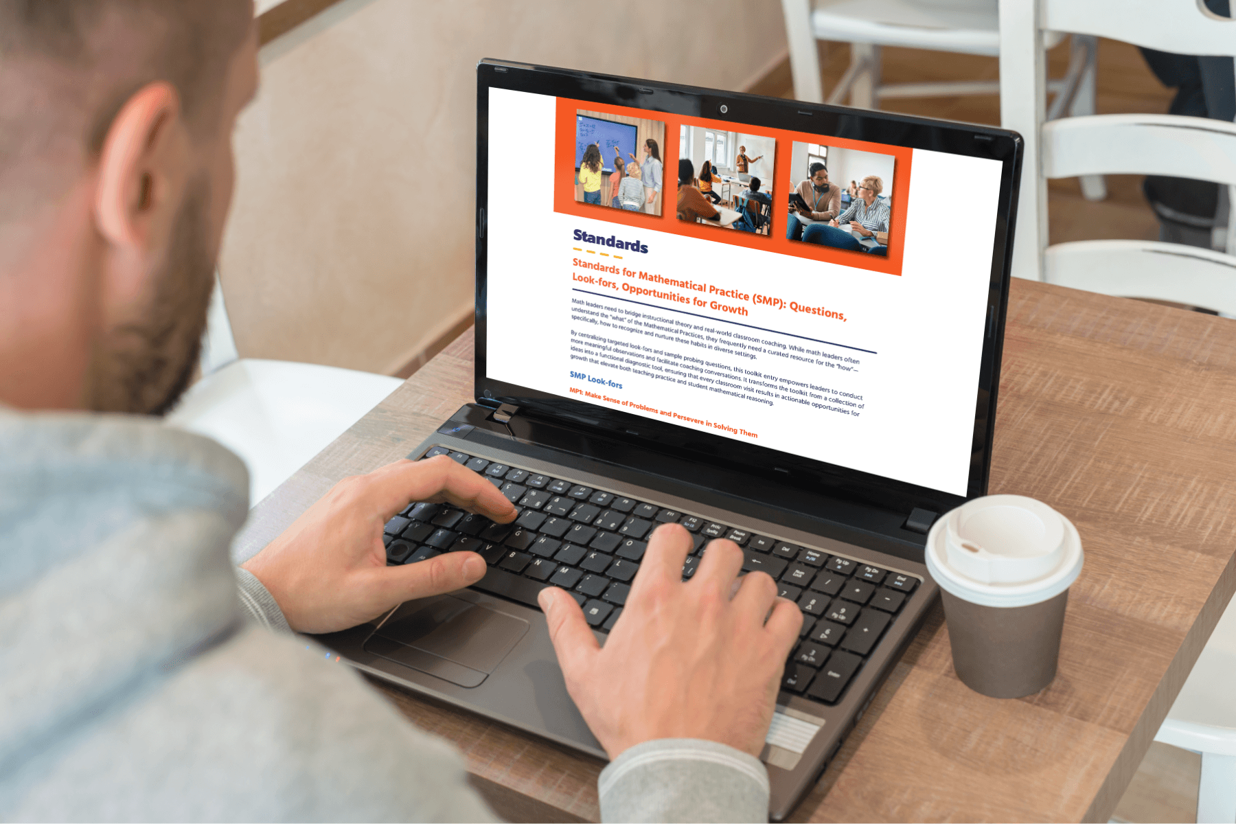 Man in a grey hoodie types on a laptop displaying the digital page of the Math Leaders' Toolkit titled "Standards" with images of people collaborating. A takeaway coffee cup beside him.