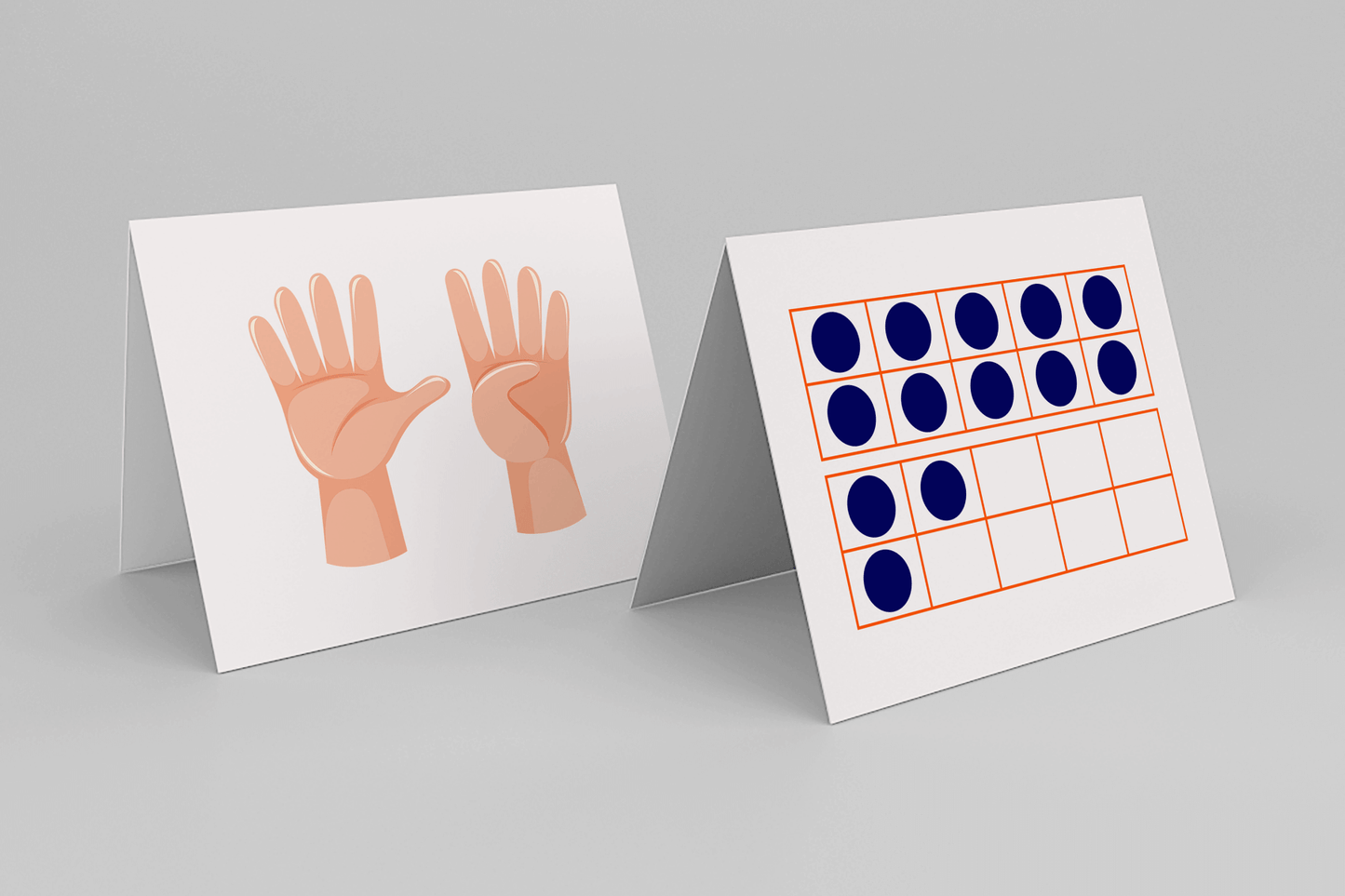 Two white, tent-style math cards are displayed upright on a light gray surface. The card on the left shows two illustrated hands with fingers spread—one with all five fingers raised and the other with four—representing the number nine. The card on the right features a twenty-frame outlined in orange, with seventeen blue dots filling the boxes, used to visually represent quantity.