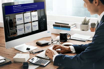 A person in business attire works at a desktop computer displaying a training module titled “Key Terms You Will Hear.” The screen shows a grid of interactive cards with payroll and tax-related terms such as One Big Beautiful Bill Act (OBBBA), Tax Cuts and Jobs Act (TCJA), Overtime Premium Rate Changes, Standard Deduction Adjustments, Dependent Care Contribution Limits, and Blended Overtime Rates. The desk has office supplies, books, a calculator, a wallet, glasses, and a coffee mug, with potted plants.