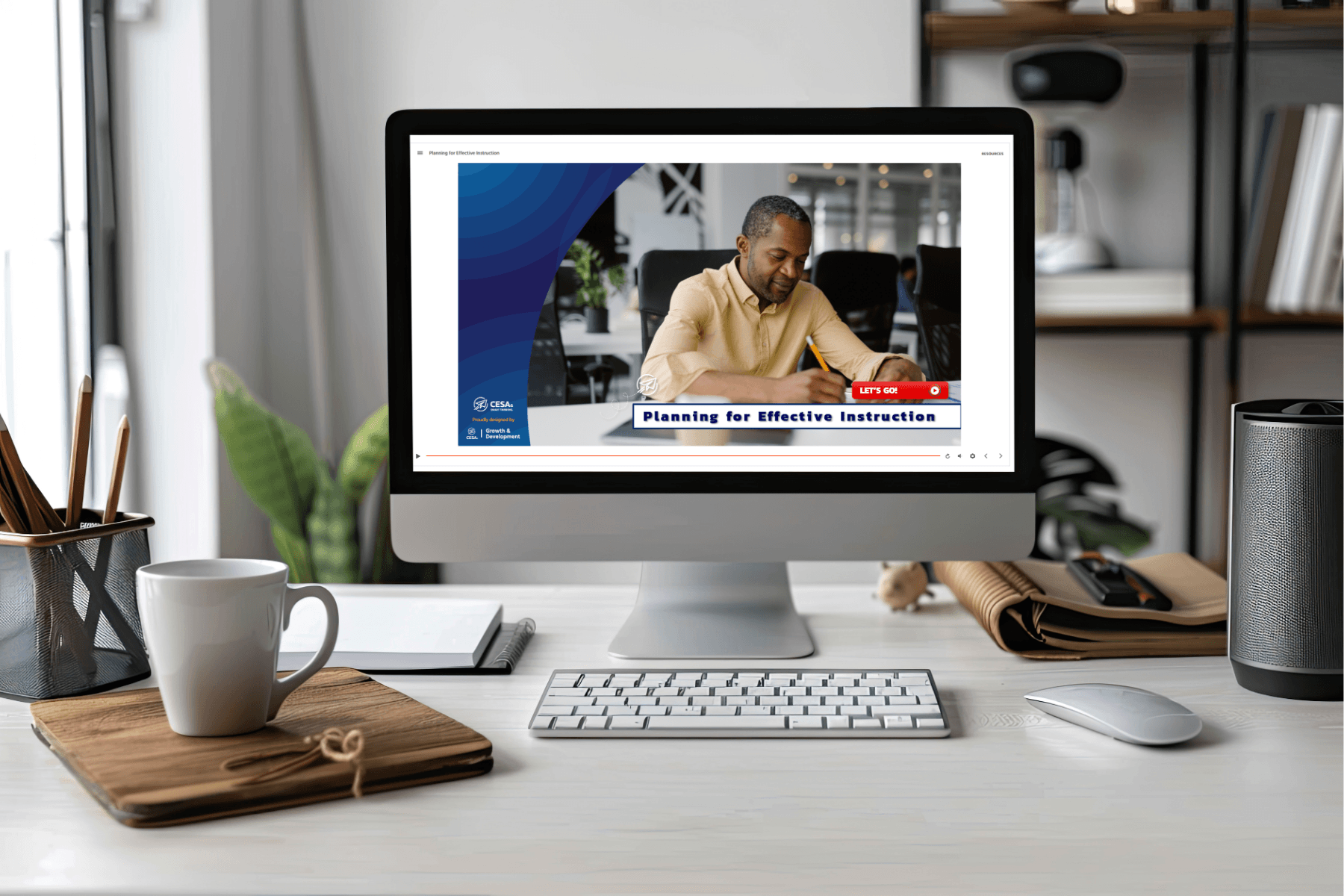 A computer screen displays a man writing, titled “Planning for Effective Instruction.” The desk holds coffee, notebooks, and a plant, evoking a calm, productive workspace.