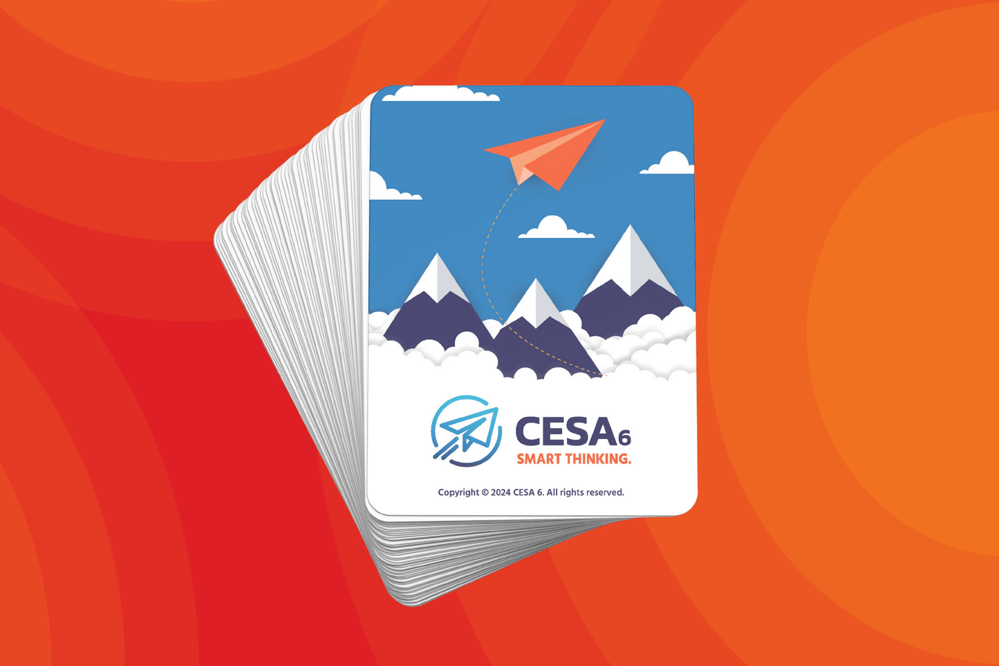 Stack of randomized grouping cards displayed on an orange gradient background. The visible card backing features an illustration of snowy mountain peaks, clouds, and a flying orange paper airplane with the text 'CESA 6 SMART THINKING' and a copyright notice at the bottom.