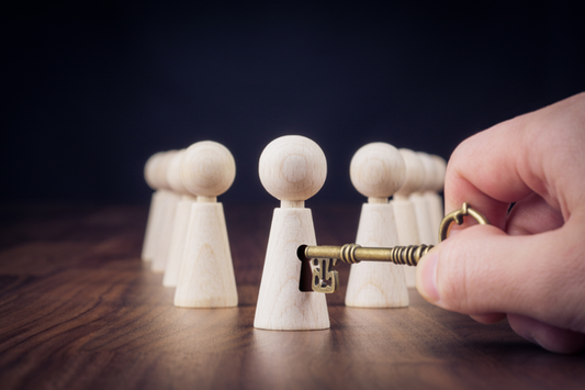 Conceptual image depicting personal growth and potential, represented by wooden figures and a key unlocking one. 