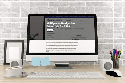 A desktop computer on a wooden desk displays a webpage titled "WISEgrants Navigation Essentials for ESEA." The scene includes speakers, a framed photo, pencils, a cup of coffee, and sticky notes, with a brick wall in the background, creating a productive and organized workspace atmosphere.