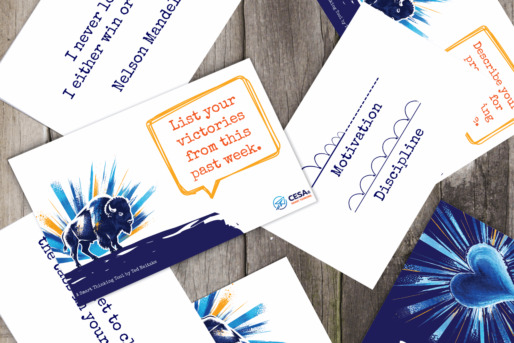A collage of motivational cards on a wooden surface. Cards feature text like "List your victories" and "Motivation," with illustrations of a bison and heart.