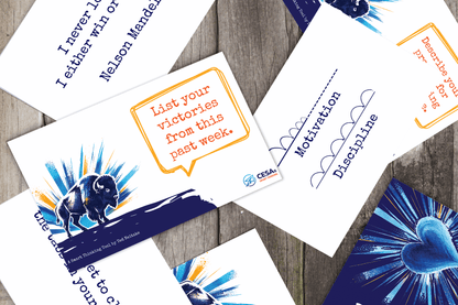 A collage of motivational cards on a wooden surface. Cards feature text like "List your victories" and "Motivation," with illustrations of a bison and heart.